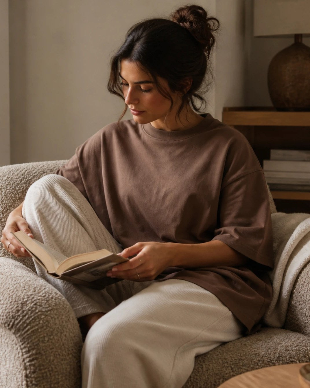 The Mocha tee worn while reading, showing how the oversized cut falls when seated.